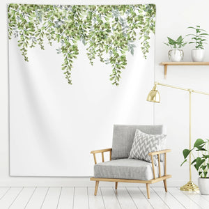 Green leaf wall tapestry, hanged on a white wall, above a gray couch
