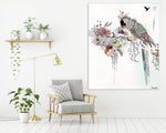 Large canvas painting of colorful parrot in the jungle, hanged on a white wall, above gray couch